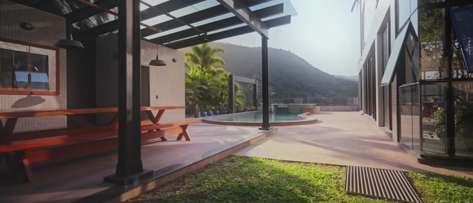 Área externa com pergolado, mesa de madeira e piscina