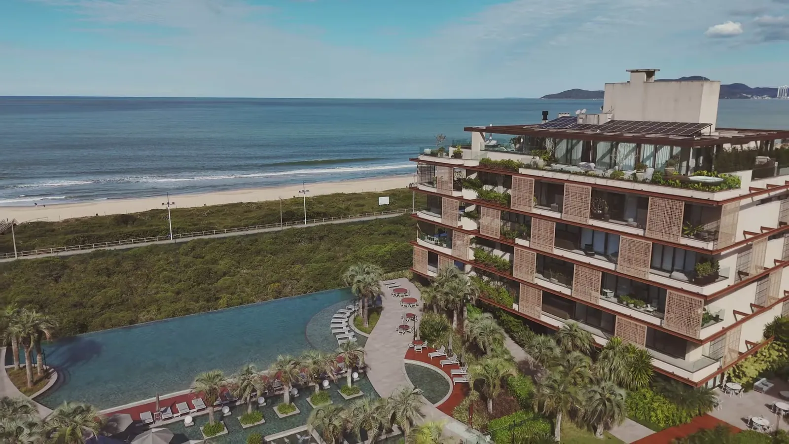 Prédio residencial com piscina e jardim de frente para o mar