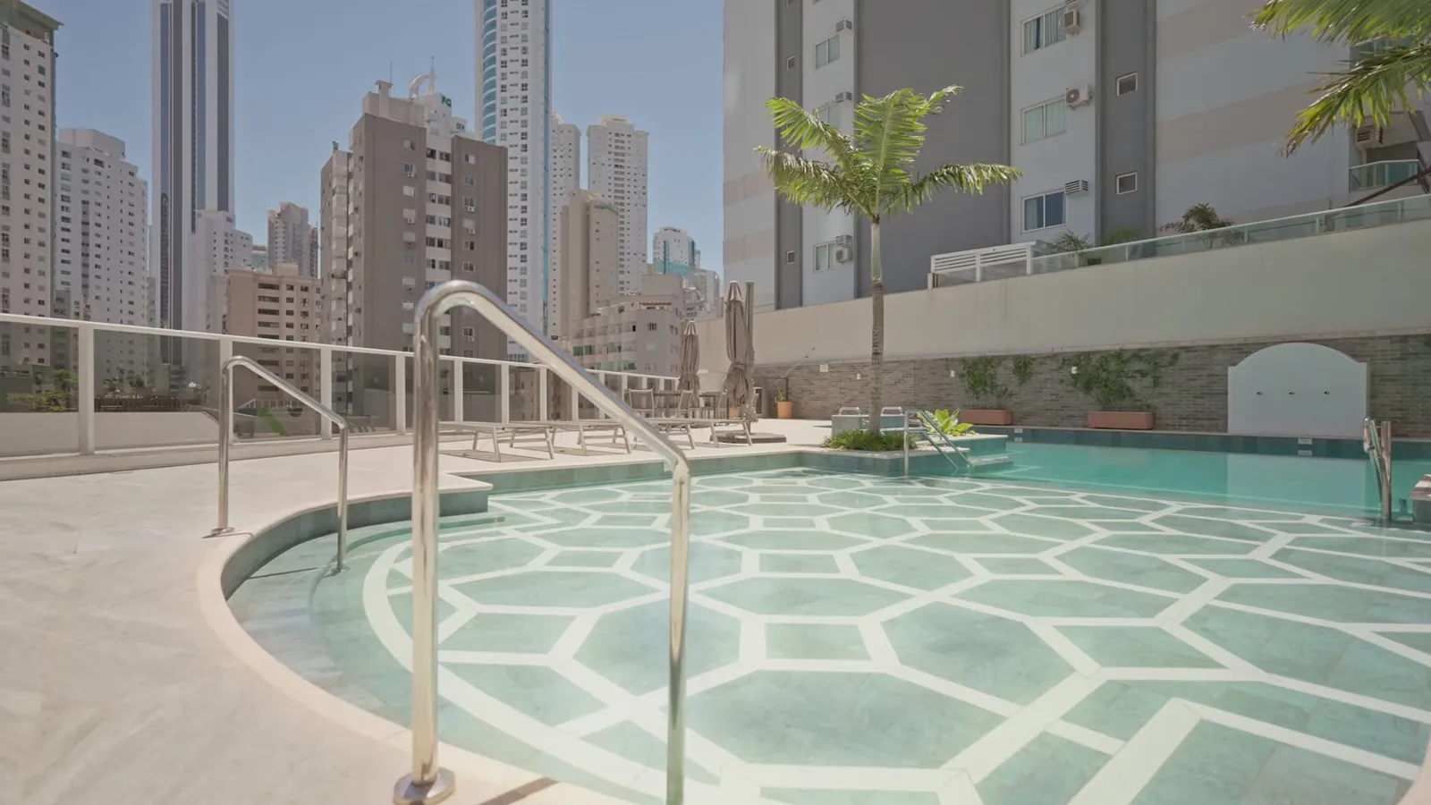 Piscina com desenho geométrico no fundo, entre prédios
